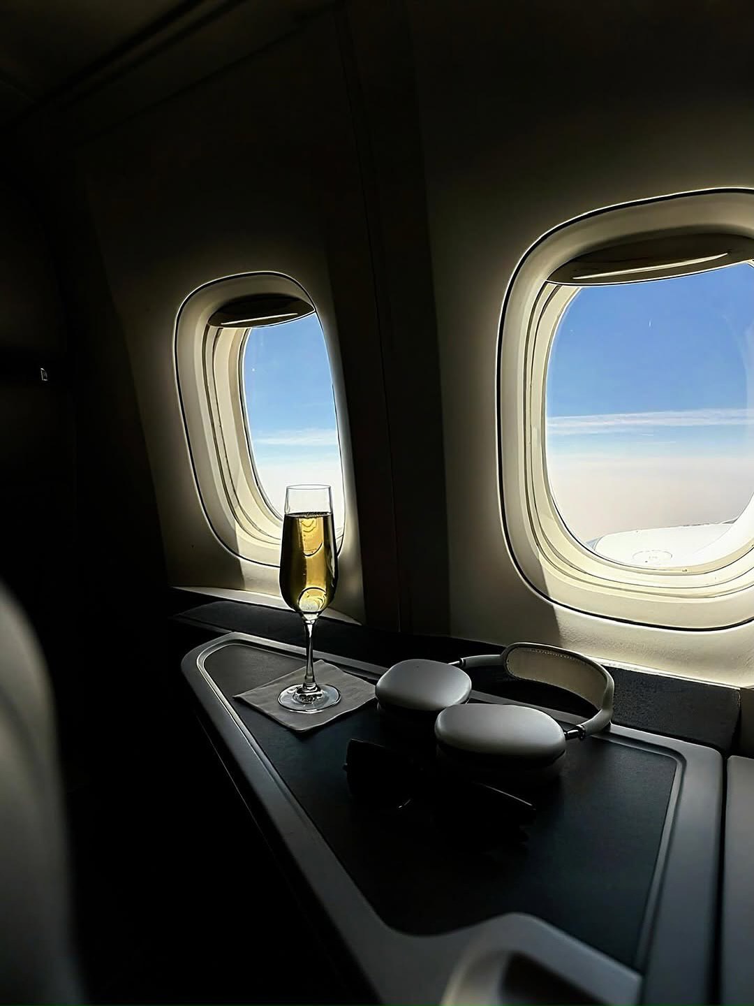 Champagne and headphones beside the windows of a private aircraft