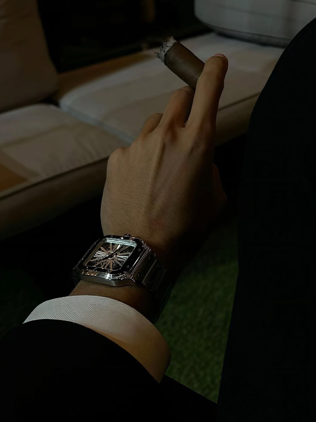 Close view of a watch and cigar against a dark lounge interior